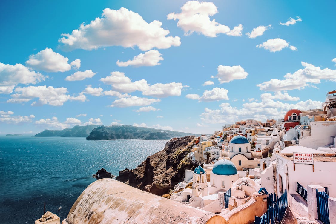 Free White Concrete House Near Body of Water Under White and Blue Cloudy Sky Stock Photo