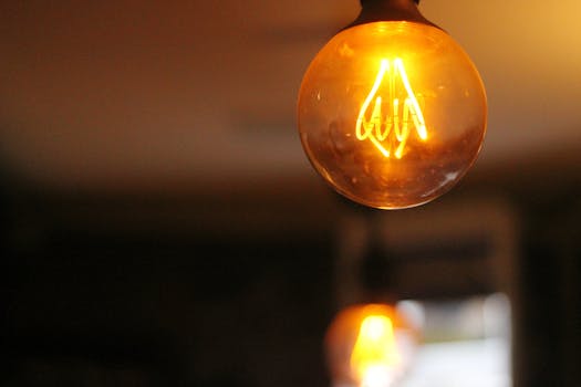 Warm, glowing vintage light bulb set against a blurred indoor background.