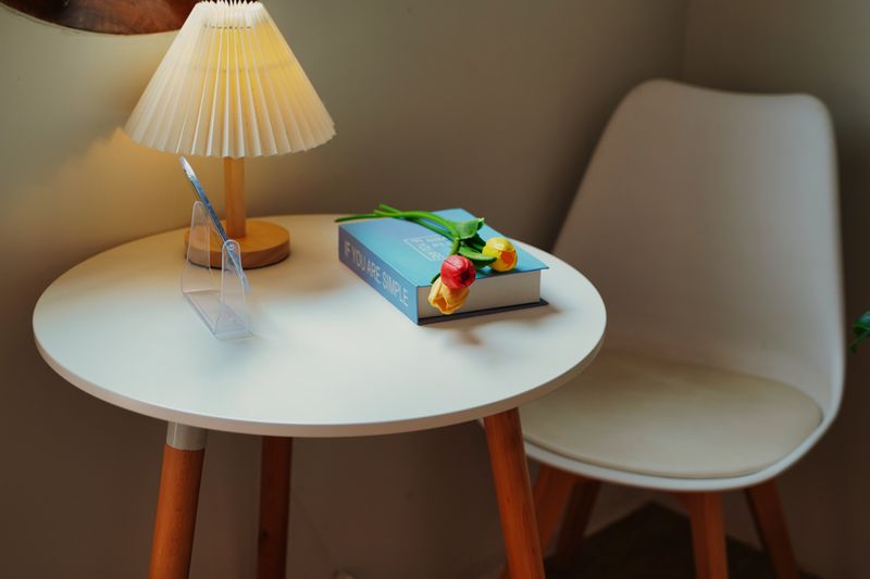 A cozy indoor setting featuring a table with tulips, a book, and a lamp.