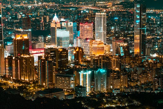 A stunning aerial view of a vibrant cityscape at night, showcasing modern skyscrapers illuminated against the night sky.