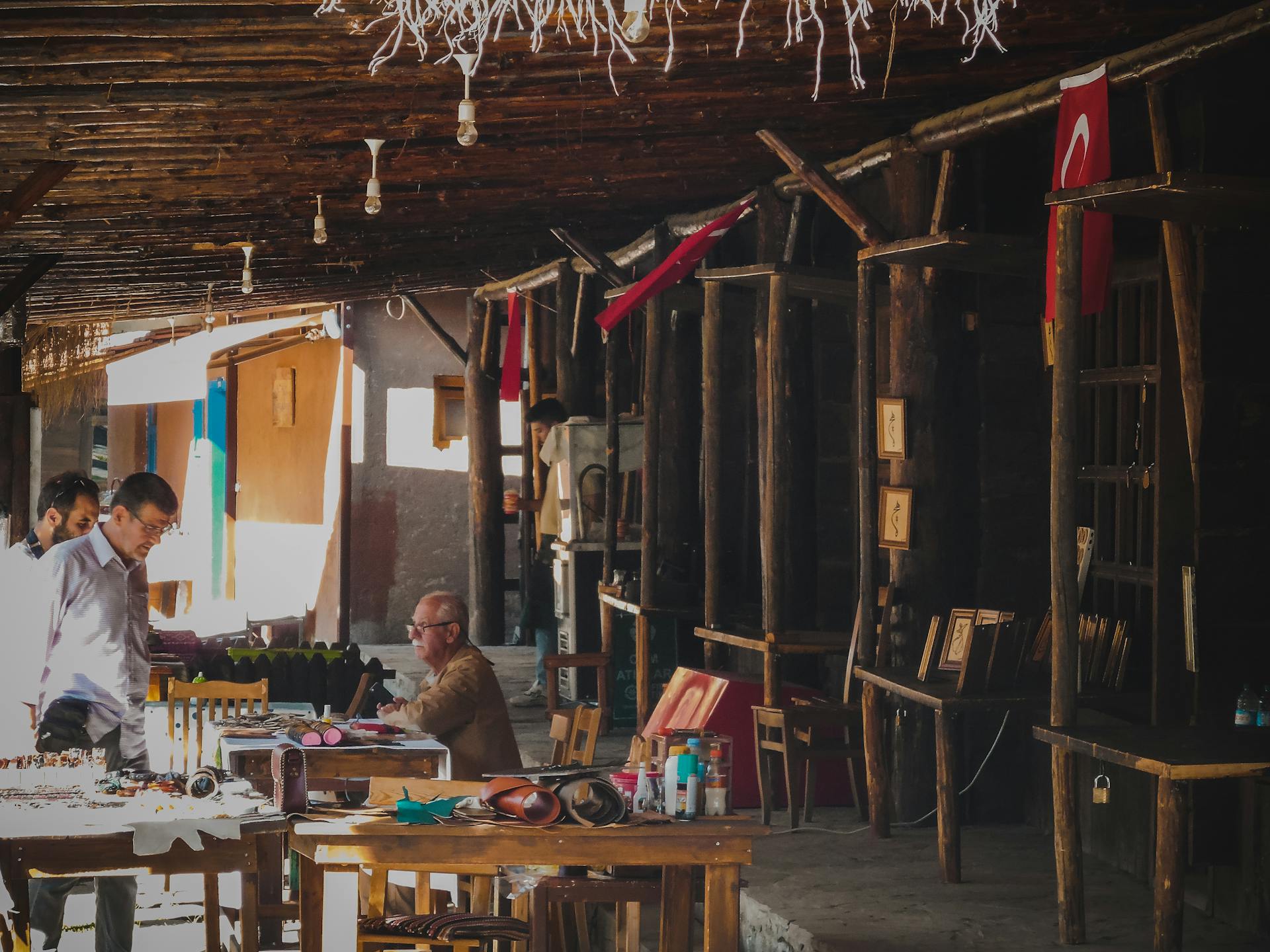 Wooden market stall at an artisan bazaar with traders and traditional Turkish flags.