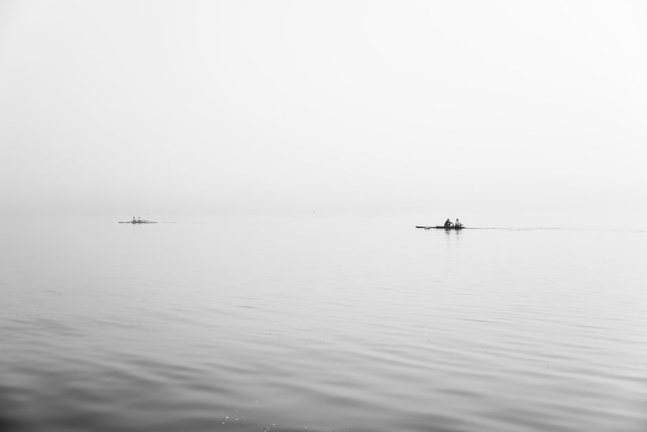 Peaceful black and white image featuring boats on calm water with a clear horizon, emphasizing serenity.