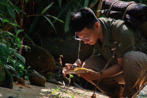 Man Writing about Plants in Notebook