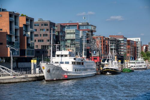 Free Modern urban riverside scene with docked boats and buildings under a clear sky. Stock Photo