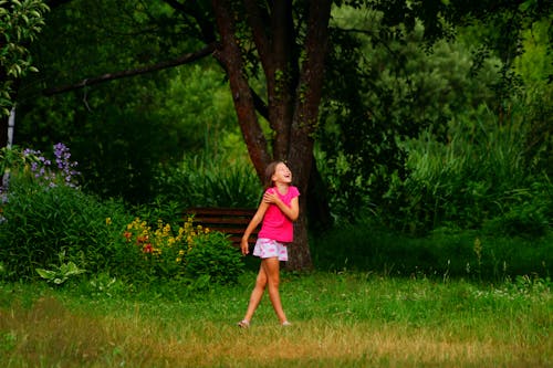 A Young Girl Laughing while Standing on Grass