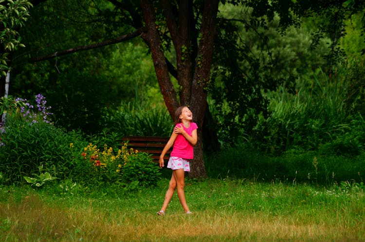 A Young Girl Laughing While Standing On Grass