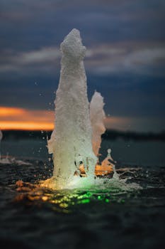 Vibrant water fountain splashing at sunset, capturing an energetic and serene atmosphere.