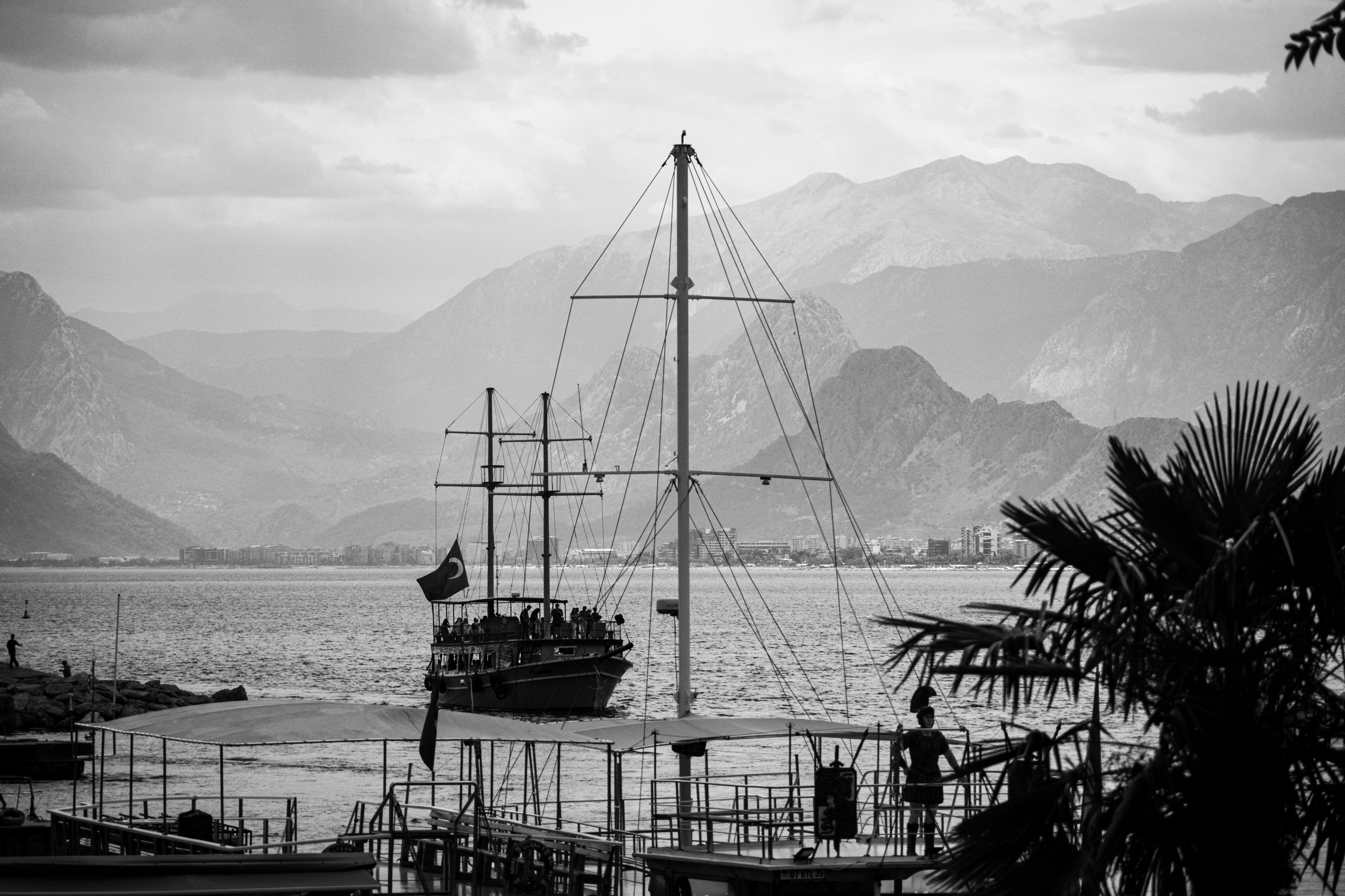 Spectacular Turkish Maldives: Adrasan Suluada Island Boat Trip Review 2026 - A dramatic black and white image showcasing a sailboat against a mountainous seascape, ideal for travel themes.