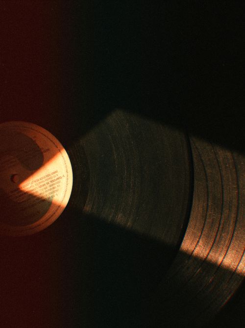 Free Close-up of a classic vinyl record with dramatic light, showcasing retro aesthetics in warm tones. Stock Photo