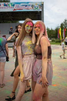 Friends covered in colorful Holi powder celebrate outdoors with joy and laughter.