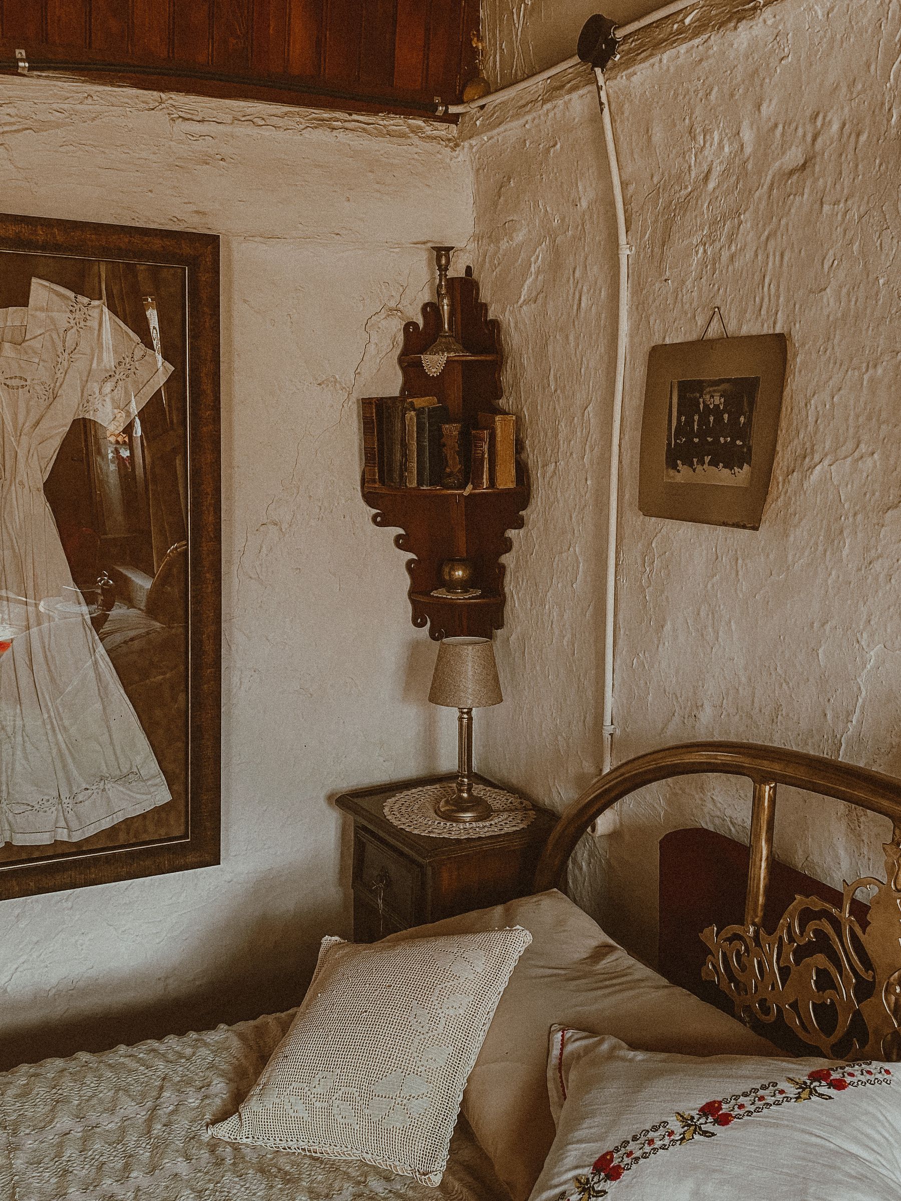 Cozy small bedroom corner with an antique-style bed, table lamp, books and compact shelving
