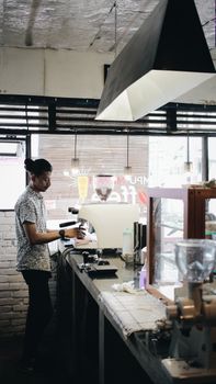Barista prepares coffee using a modern machine in a stylish cafe setting, creating a cozy atmosphere.