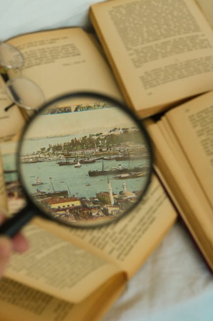 An artistic shot of open vintage books with a magnifying glass highlighting a seascape image.