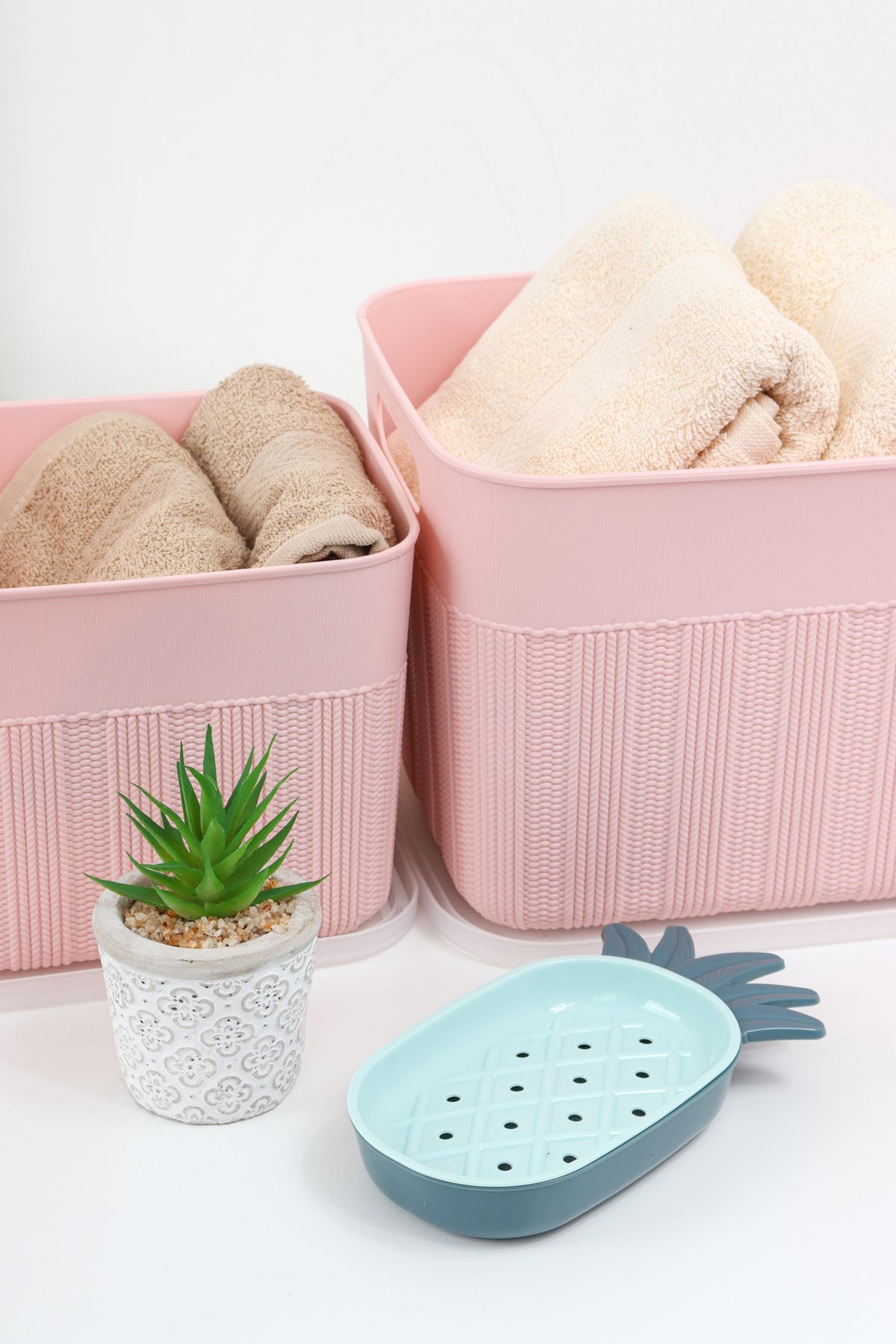 Rolled cream-colored towels arranged neatly in pastel pink storage trays