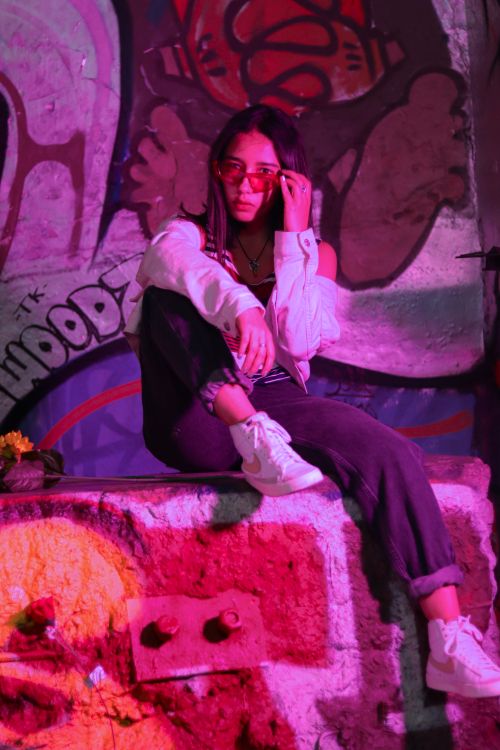Free Stylish woman posing in urban graffiti backdrop with vibrant colors in Mexico City. Stock Photo