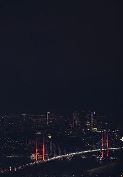 A vibrant suspension bridge illuminated at night with cityscape background, showcasing urban lights.