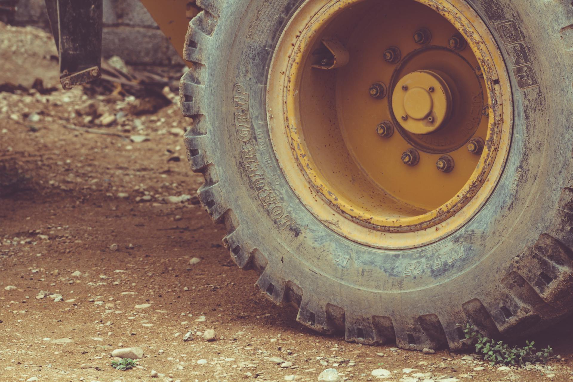 Heavy equipment tire on a dirt road in Salalah, Oman, showcasing rugged machinery.