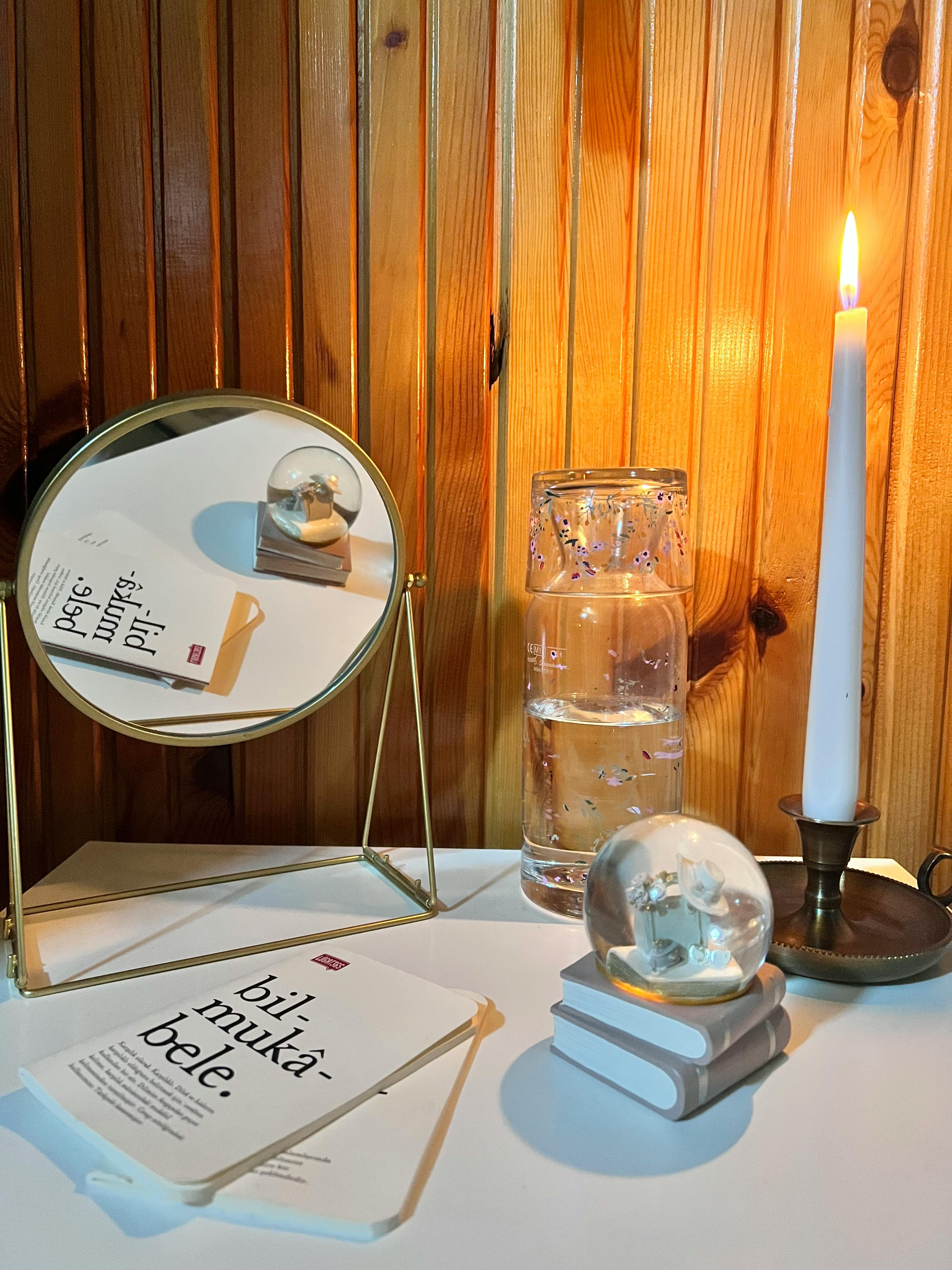 Free Elegant still life with candle, mirror, and decor in a warm interior setting. Stock Photo