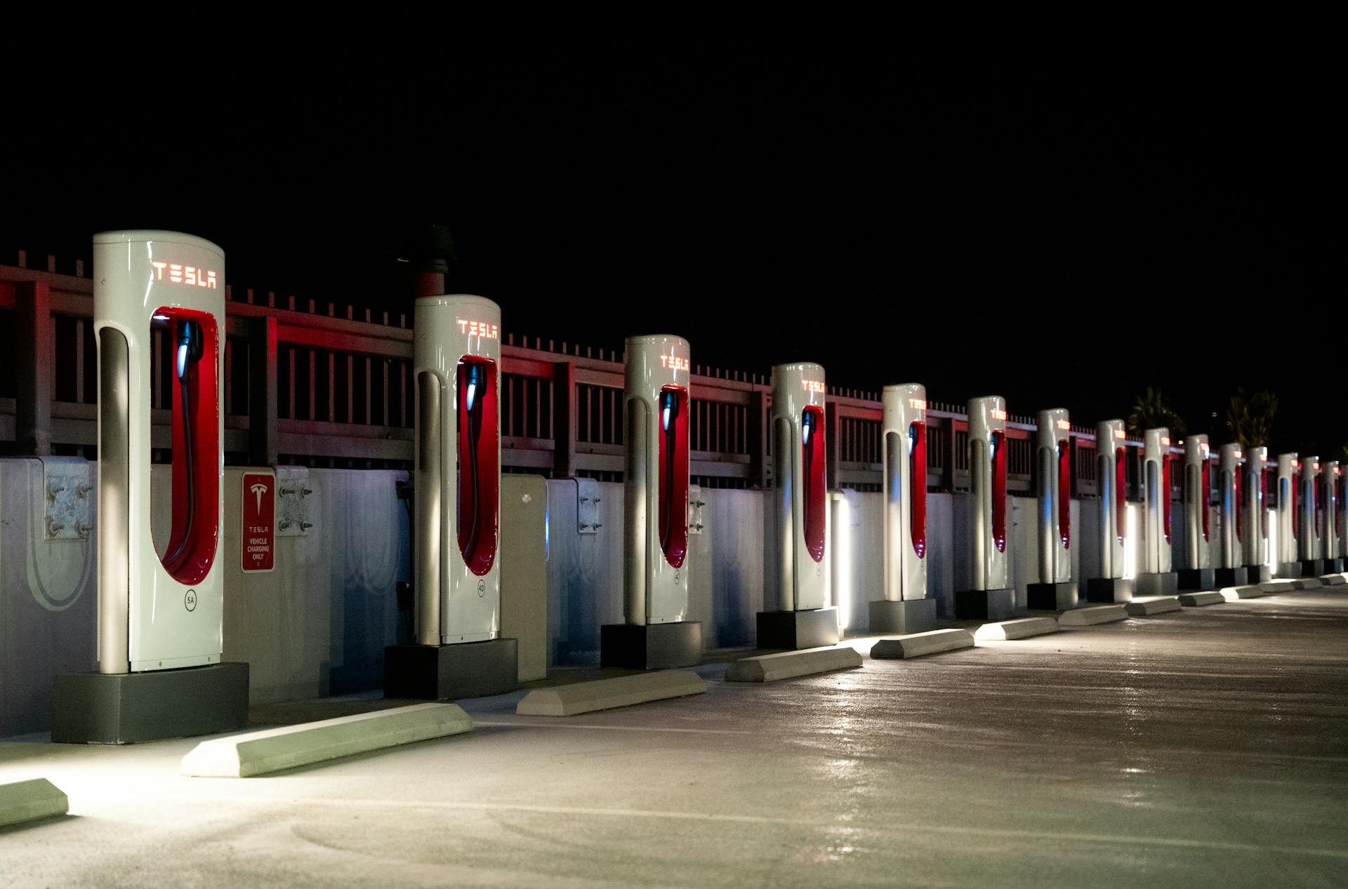 A row of Tesla charging stations illuminated at night in Redlands, CA.