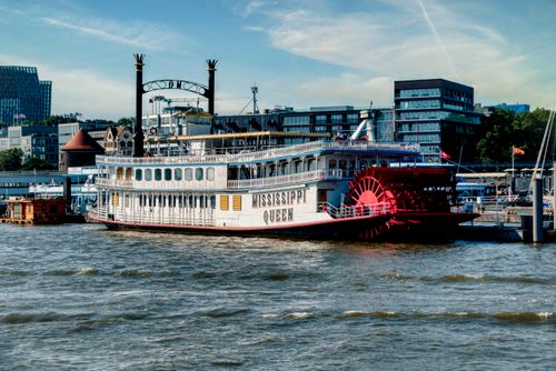 Free Elegant paddle steamer Mississippi Queen docked at urban waterfront under clear skies. Stock Photo