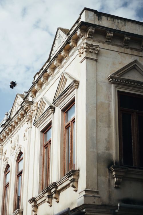 Free Low angle view of a classic building facade with ornate architecture under a blue sky. Stock Photo