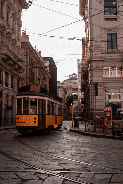 Free A Tram Moving Between Old Buildings in the City Stock Photo