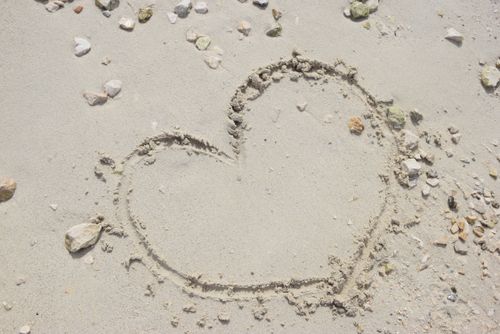 Free A heart shape drawn in the sand surrounded by small pebbles on a Croatian beach. Perfect for love-themed designs. Stock Photo