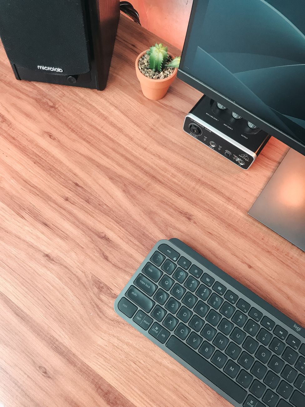 Overhead view of a clean and modern workspace featuring a keyboard and monitor on a wooden desk.