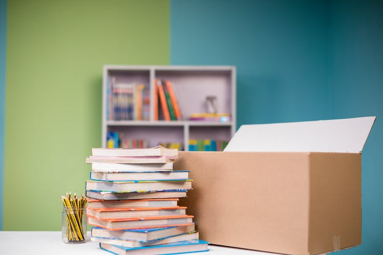 Close-up Photo Of Stacked Books Beside A Carton Box 