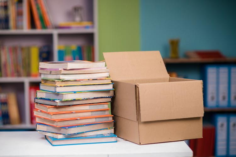 Stack Of Books Beside A Cardboard Box