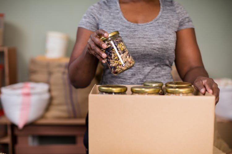 Putting Of Mixed Nuts In Glass Containers On A Box 