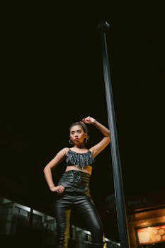 Model striking a pose in chic outfit under city lights. Urban fashion night photoshoot.