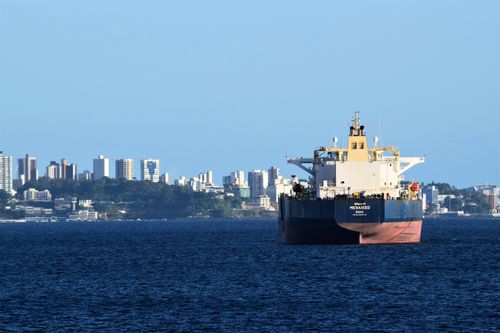 Free A cargo ship anchored in Salvador, Brazil's harbor with the city skyline in the backdrop. Stock Photo