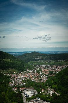 A beautiful aerial view showcasing a quaint countryside town nestled among lush green mountains under a clear sky.