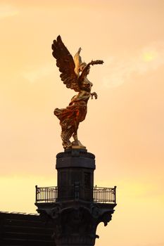 The Angel of Independence statue in Mexico City glows golden at sunset, a symbol of victory.