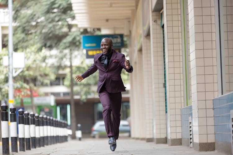 Happy Man In A Suit Jumping On A Sidewalk 