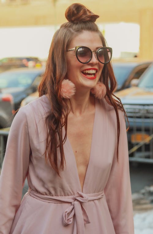 Free A Woman in Pink Dress Smiling while Wearing Sunglasses Stock Photo