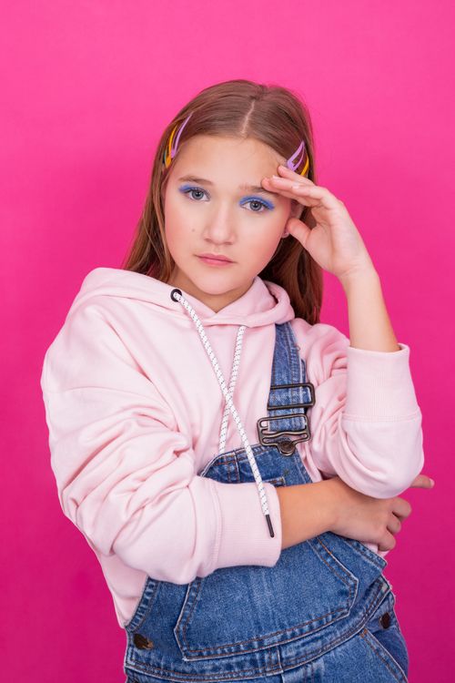 Free Portrait of a teenage girl in denim overalls against pink studio background. Stock Photo
