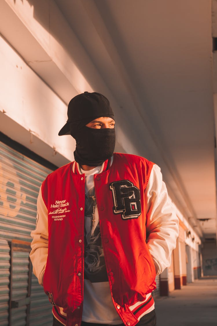 Man In A Baseball Jacket Wearing A Black Balaclava 