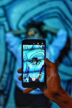 A smartphone captures a person with colorful street art background in Mexico City.