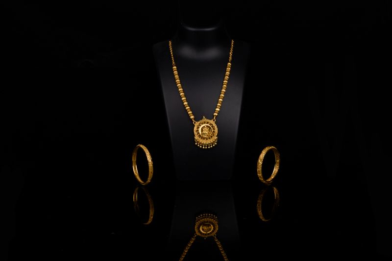 Luxurious gold necklace and bangles elegantly displayed against a dark backdrop