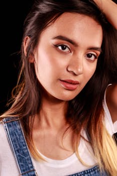 Close-up portrait of a young woman with ombre hair, wearing denim, against a dark background.