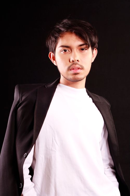 Free A confident young man poses against a black background in a studio setting. Stock Photo