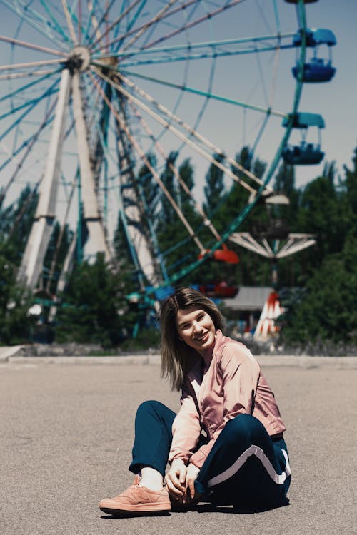 Woman Sitting Near Ferris Wheel