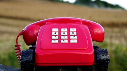 gratis Rode Roterende Telefoon Met Zwarte Wielen In De Buurt Van Bruine Grassen Overdag Stockfoto