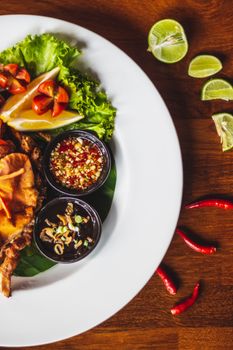 A colorful Thai dish with fresh lime and spices on a wooden table, featuring vibrant garnishes.