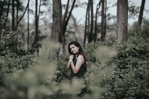 Free A woman standing amidst lush green trees in a serene forest setting. Stock Photo