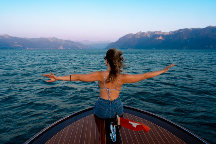 A Back View Of A Woman In Bikini Top Sitting On The Boat While Facing The Ocean