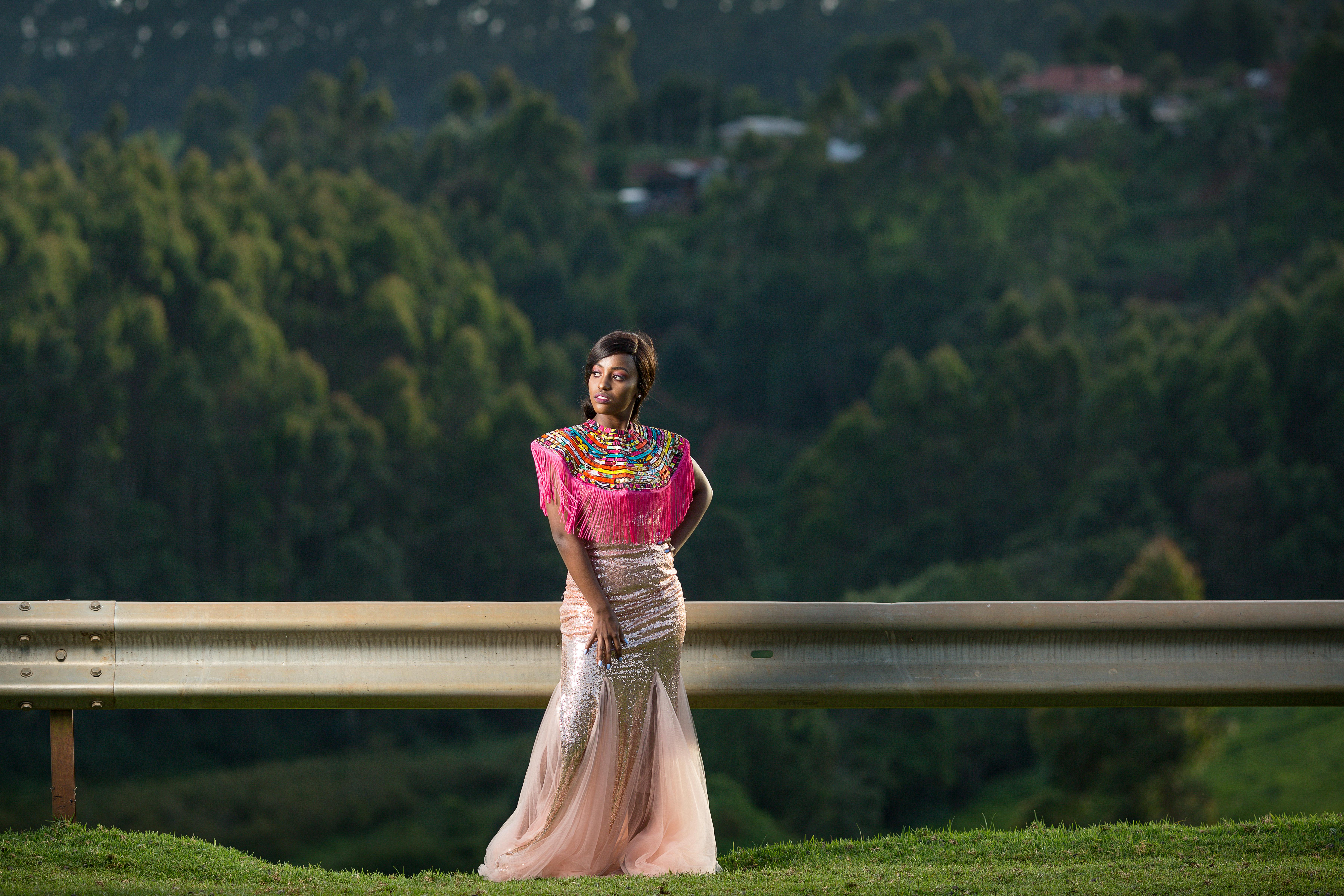 woman wearing traditional thai hmong and glitter long gown posing beside highway guardrail