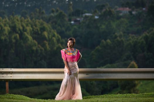 Woman in Pink and White Floral Dress Standing on Green Grass Field